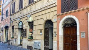 A historic building with a cobblestone street, a shop with a sign, and a large wooden door.