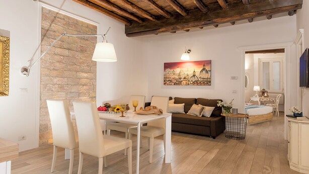 A cozy living room with a dining area, a stone wall, a painting, and a wooden ceiling.