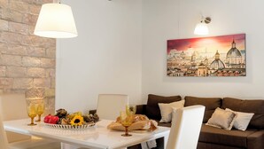 A cozy living area with a white table, brown sofa, and a cityscape painting on the wall.