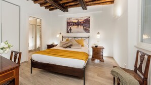 A bedroom with a wooden bed, a nightstand, a chair, and a painting on the wall.