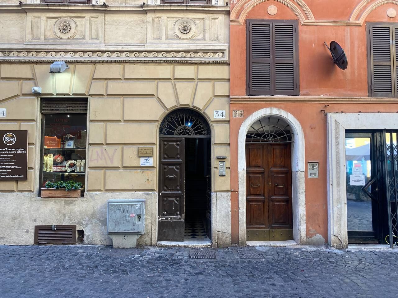 A building with a shop on the ground floor, a wooden door, and a sign with a number.