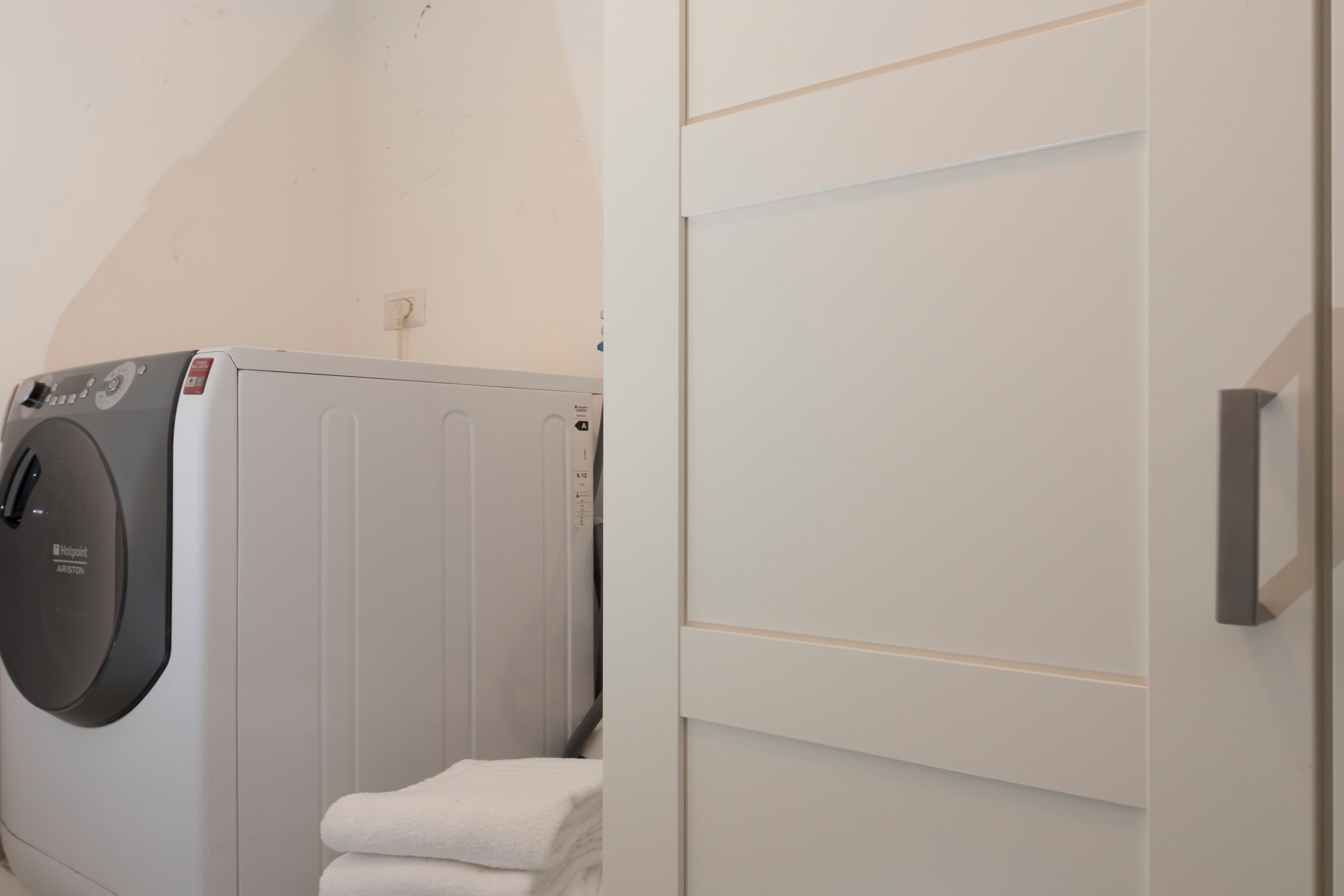 A laundry area with a front-loading washing machine and stacked towels.