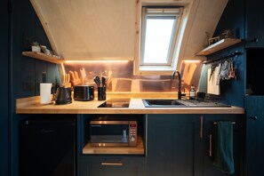 A compact kitchen with a built-in microwave, a sink, and a window above the countertop.