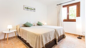 Un dormitorio con una cama, dos mesitas de noche, una lámpara, una ventana con cortinas y un cuadro colgado en la pared.