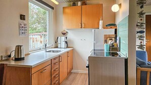 Une cuisine compacte avec des meubles en bois, une bouilloire en acier inoxydable, une machine à café et un réfrigérateur.
