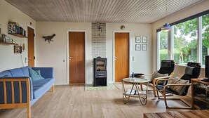 Un salon chaleureux avec un canapé bleu, des chaises en bois, une petite table et une cheminée.