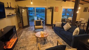 A cozy living room with a fireplace, comfortable seating, and a view of the outdoors.