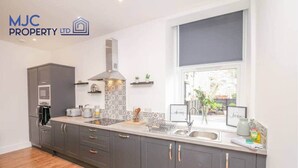 A modern kitchen with grey cabinets, a built-in oven, and a large window. - Mansfield - sleeps 8 guests  in 3 bedrooms (Hawick)