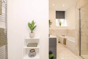Un baño moderno con un tocador blanco, una ducha y piso de mármol.