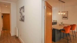 A modern kitchen with a wooden island, two pendant lights, and orange bar stools. - Mansfield - sleeps 8 guests  in 3 bedrooms (Hawick)
