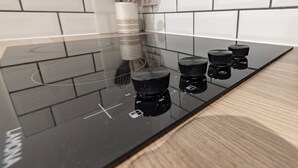 A kitchen with a black induction cooktop, four knobs, and a white tiled backsplash. - Riverside - sleeps 6 guests  in 2 bedrooms (Hawick)