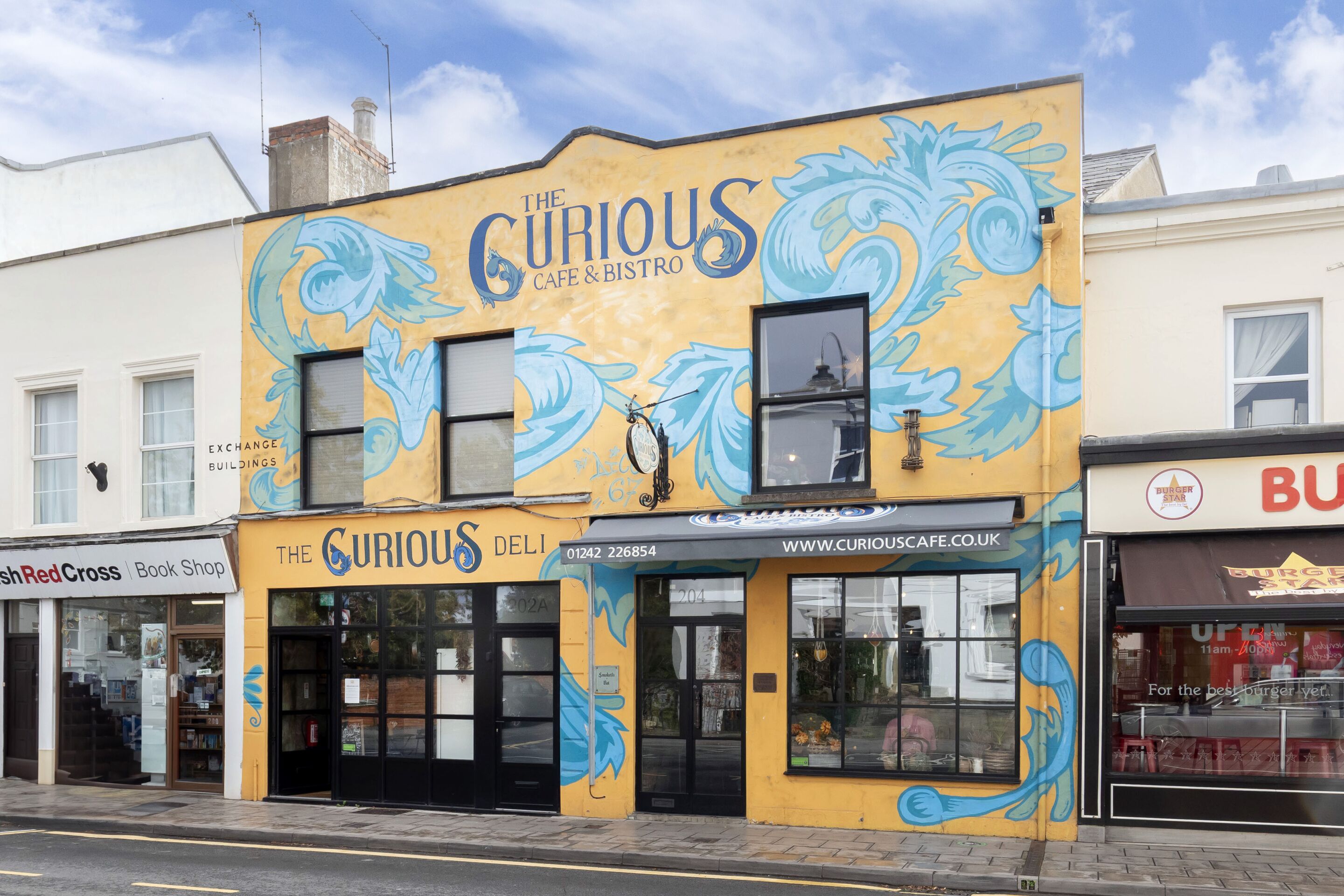 Un bâtiment orné d’une fresque représentant un poisson bleu, et sur lequel on peut lire l’inscription « The Curious Cafe & Bistro ».