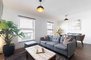A modern living room with a grey sofa, a wooden coffee table, and a large potted plant.