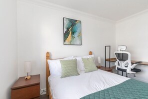 A neatly arranged hotel room with a bed, bedside tables, a chair, and a painting on the wall.