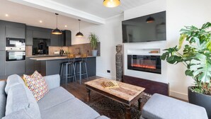 Uma sala de estar moderna com um sofá cinzento, uma mesa de centro de madeira e uma lareira.