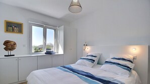Une chambre avec un grand lit, une fenêtre donnant sur un beau paysage et un luminaire au plafond.