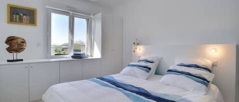 A bedroom with a large bed, a window with a view, and a ceiling light fixture.