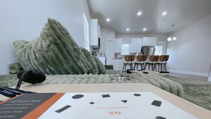 A modern, well-lit room with a large bed, a desk, and a dining area. - 10 min to Casino, brand new 2b/1b single home 2025 (Durant)