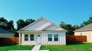 A single-story house with a front porch, a garage, and a well-maintained lawn. - 10 min to Casino, brand new 2b/1b single home 2025 (Durant)