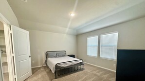 Un dormitorio con cama, armario y dos ventanas con persianas.