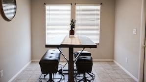 Un comedor con una mesa, cuatro sillas y una planta en maceta.