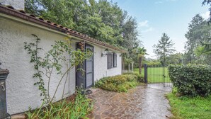 Een pad van stenen dat leidt naar een wit gebouw met zwarte luiken en een pannendak.