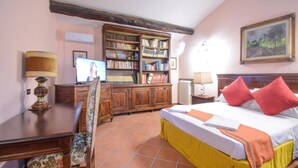 Een slaapkamer met een bed, bureau, stoel, boekenkast en een schilderij aan de muur.