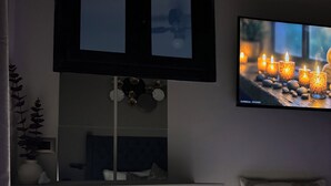 Makuuhuoneessa on sänky, yöpöytä, lamppu, sängyn yläpuolelle asennettu televisio ja hylly, jossa on koriste-esineitä.