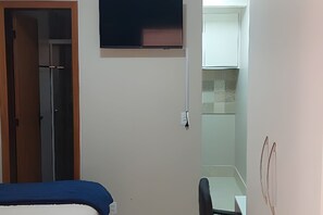 Ein Schlafzimmer mit Bett, Kleiderschrank, kleinem Tisch und einem an der Wand befestigten Fernseher.