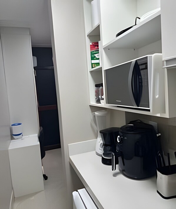 Eine moderne Küche mit weißen Schränken, einer Mikrowelle, einer Kaffeemaschine und einem Wasserkocher.