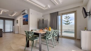 A modern dining area with a table set for four, surrounded by green chairs with cut-out designs. - Amazing home in Trabia (Trabia)