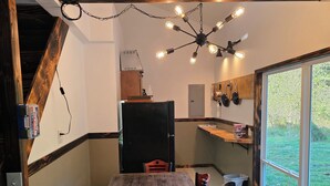 Comedor con mesa y sillas de madera, ventilador de techo y vistas al exterior a través de un ventanal amplio.