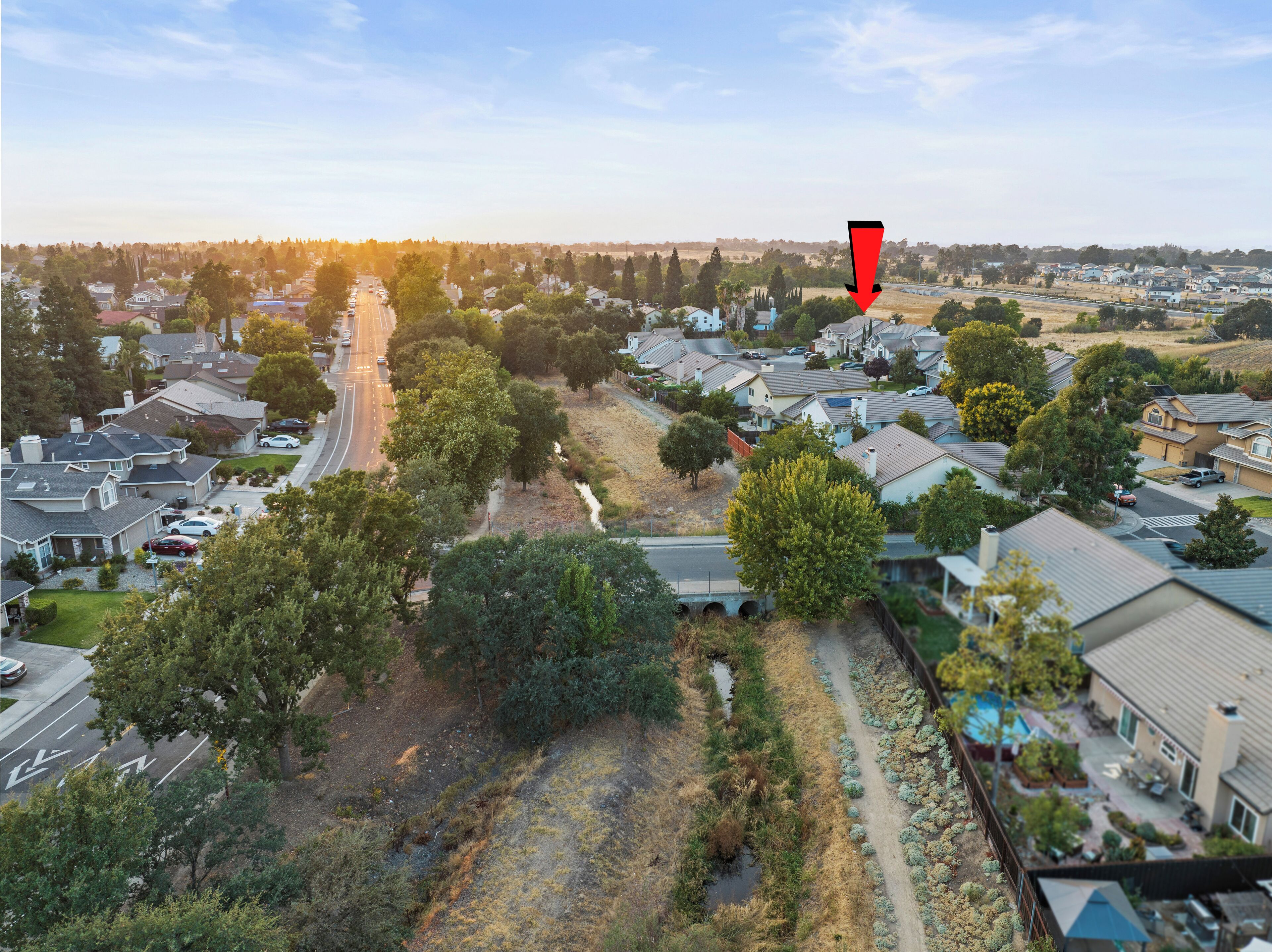 An aerial view of a residential area with houses, roads, and greenery.