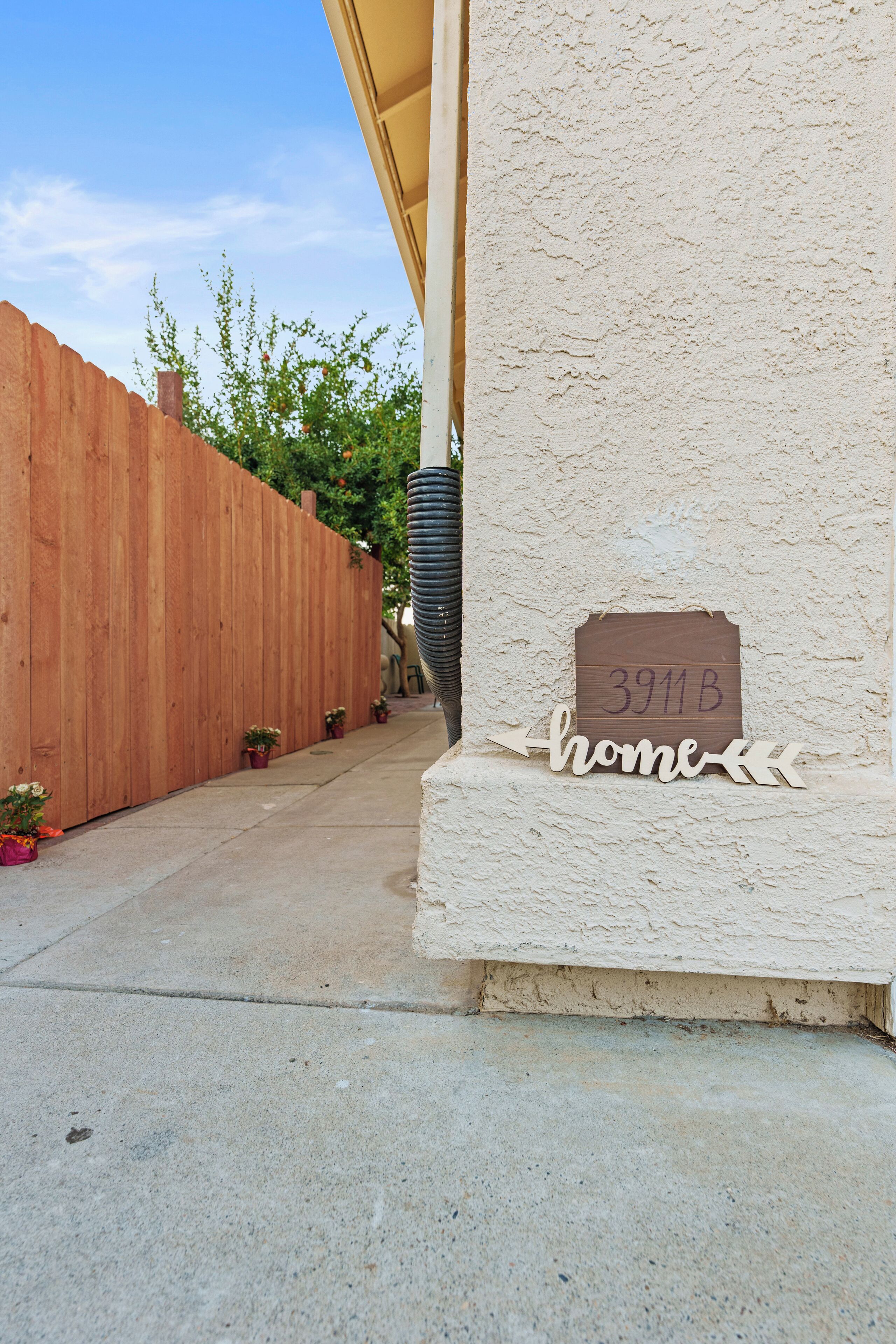 Una casa con cerca de madera, un sendero de concreto y un letrero que indica la dirección '3911B home'.