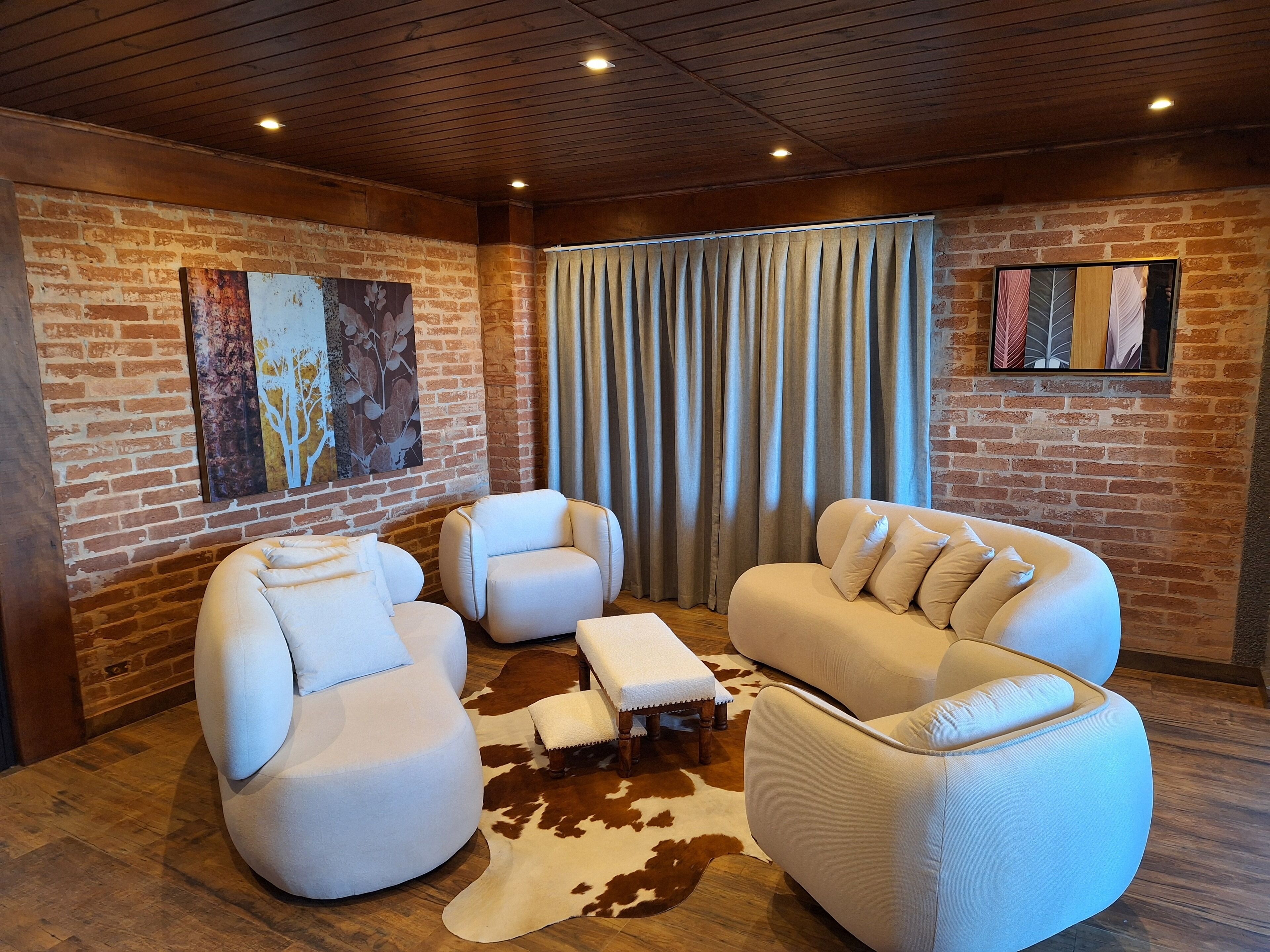 Una habitación acogedora con pared de ladrillo, un ventanal con cortinas y una alfombra de cuero de vaca.