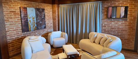 Una habitación acogedora con pared de ladrillo, un ventanal con cortinas y una alfombra de cuero de vaca.