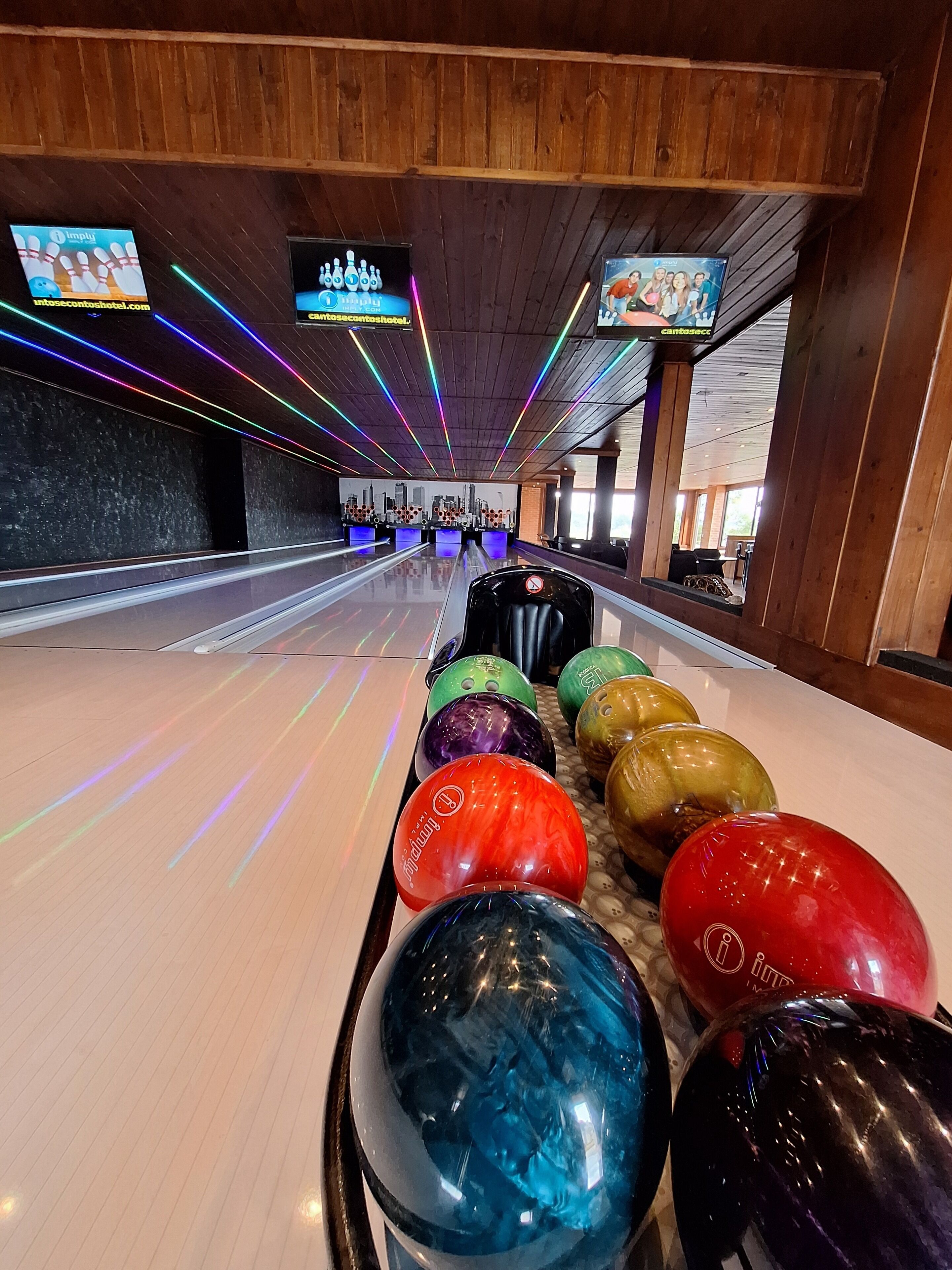 A bowling alley with multiple lanes, colorful bowling balls, and neon lights.
