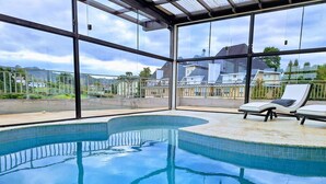 A swimming pool with a curved design, surrounded by a glass enclosure. - Château Suisse Boutique Hotel (Campos do Jordão)
