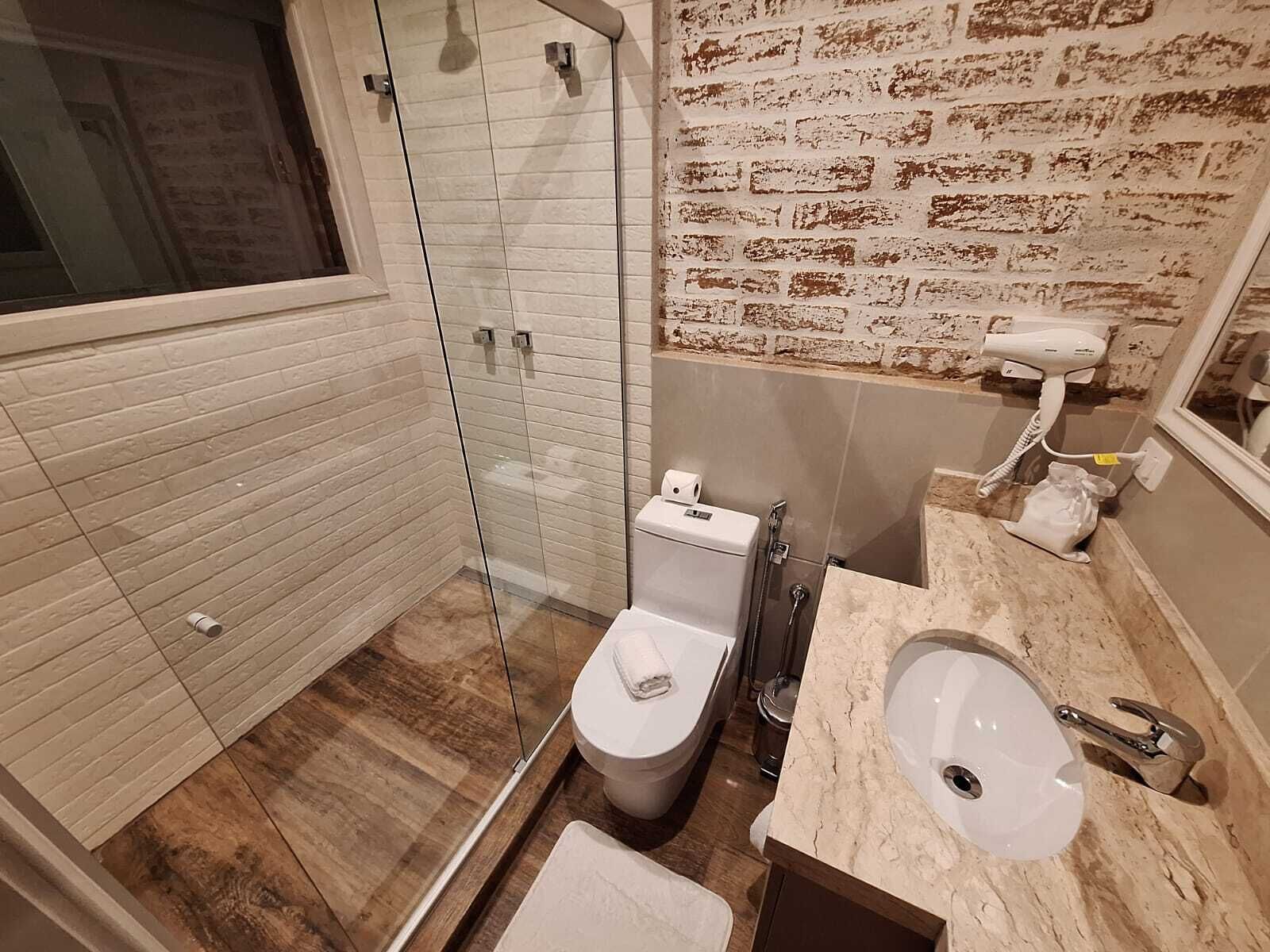 Un baño moderno con ducha de vidrio, inodoro y lavamanos.