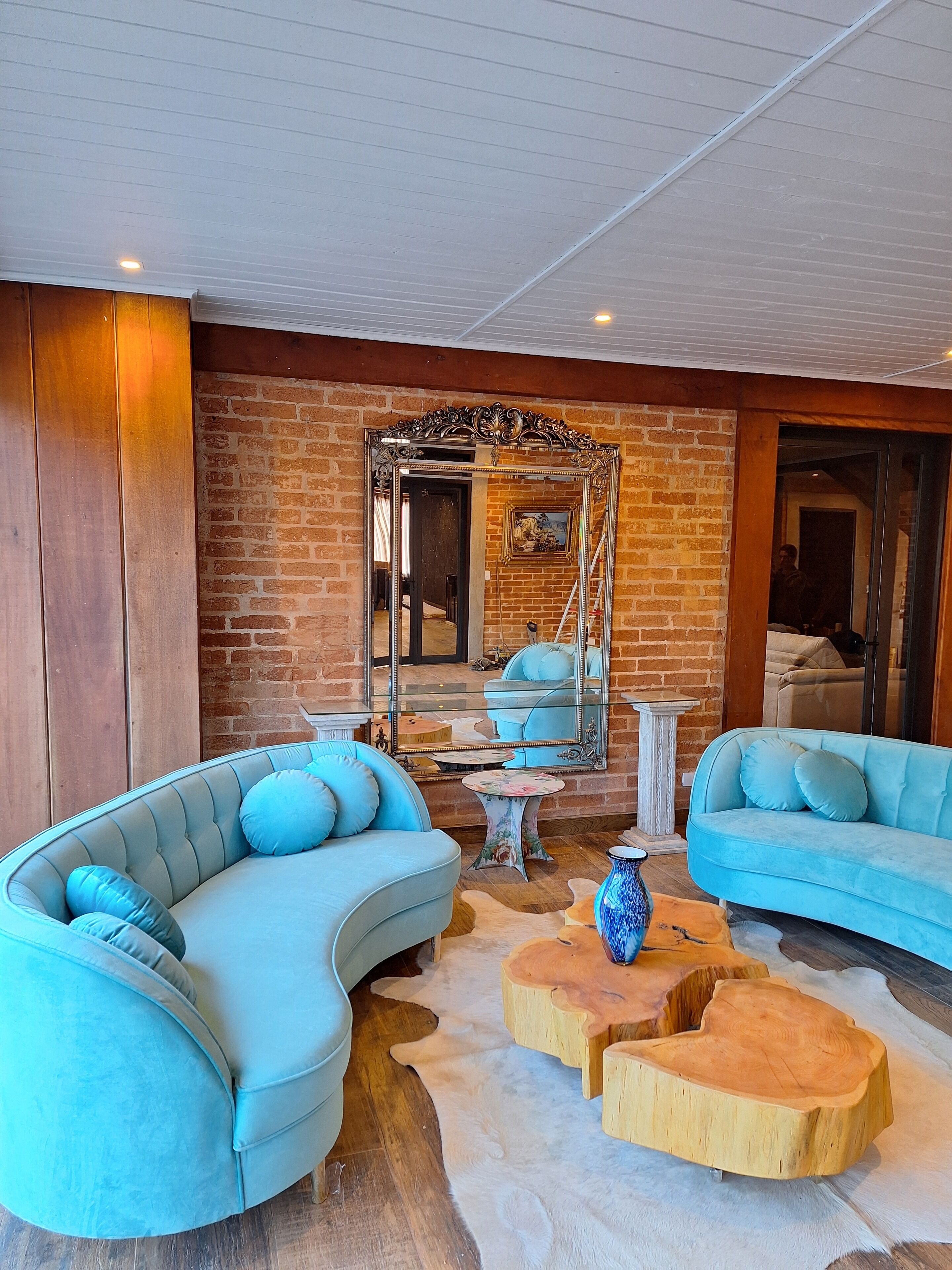 A modern living room with a curved blue sofa, a wooden coffee table, and a large mirror reflecting the room.