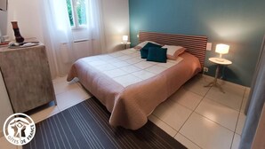 A bedroom with a bed, bedside tables, a window with curtains, and a nightstand. - Gîtes de France® - Le Cocon (PRAYSSAC)