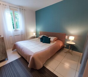 Une chambre à coucher avec un lit, des tables de chevet, une fenêtre avec des rideaux et une petite table de nuit.