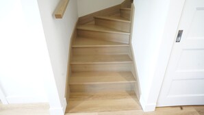 A wooden staircase with a handrail, leading to a white door.
