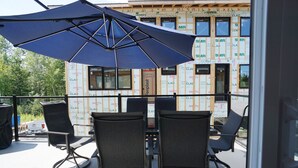 An outdoor patio with two chairs and a table, an umbrella, and a building under construction in the background.