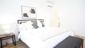 A neatly arranged bedroom with a bed, bedside table, and a bench.
