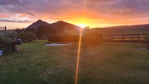 A sunset over a grassy field with a mountain in the background.
