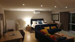 A hotel room with a bed, a desk, a chair, a sofa, and a window.