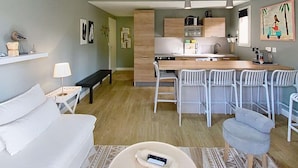 A modern living room with a sofa, a round coffee table, and a dining area with chairs. - Apartment for 4 people, on the Lacanau Ocean golf course (LACANAU OCEAN)