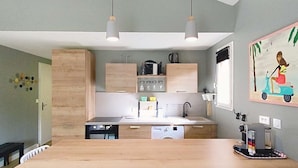 A modern kitchen with a central island, white chairs, pendant lights, and a painting on the wall. - Apartment for 4 people, on the Lacanau Ocean golf course (LACANAU OCEAN)