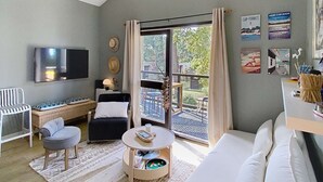 A modern living room with a sofa, a TV, a desk, and a balcony with a view. - Apartment for 4 people, on the Lacanau Ocean golf course (LACANAU OCEAN)